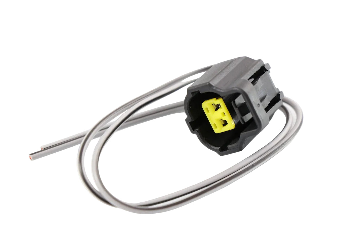 Advance Truck Parts USA W094110 2-pin pigtail connector showing an angled view of the black plastic housing, yellow internal insert, and attached grey wires with stripped ends on a plain white background