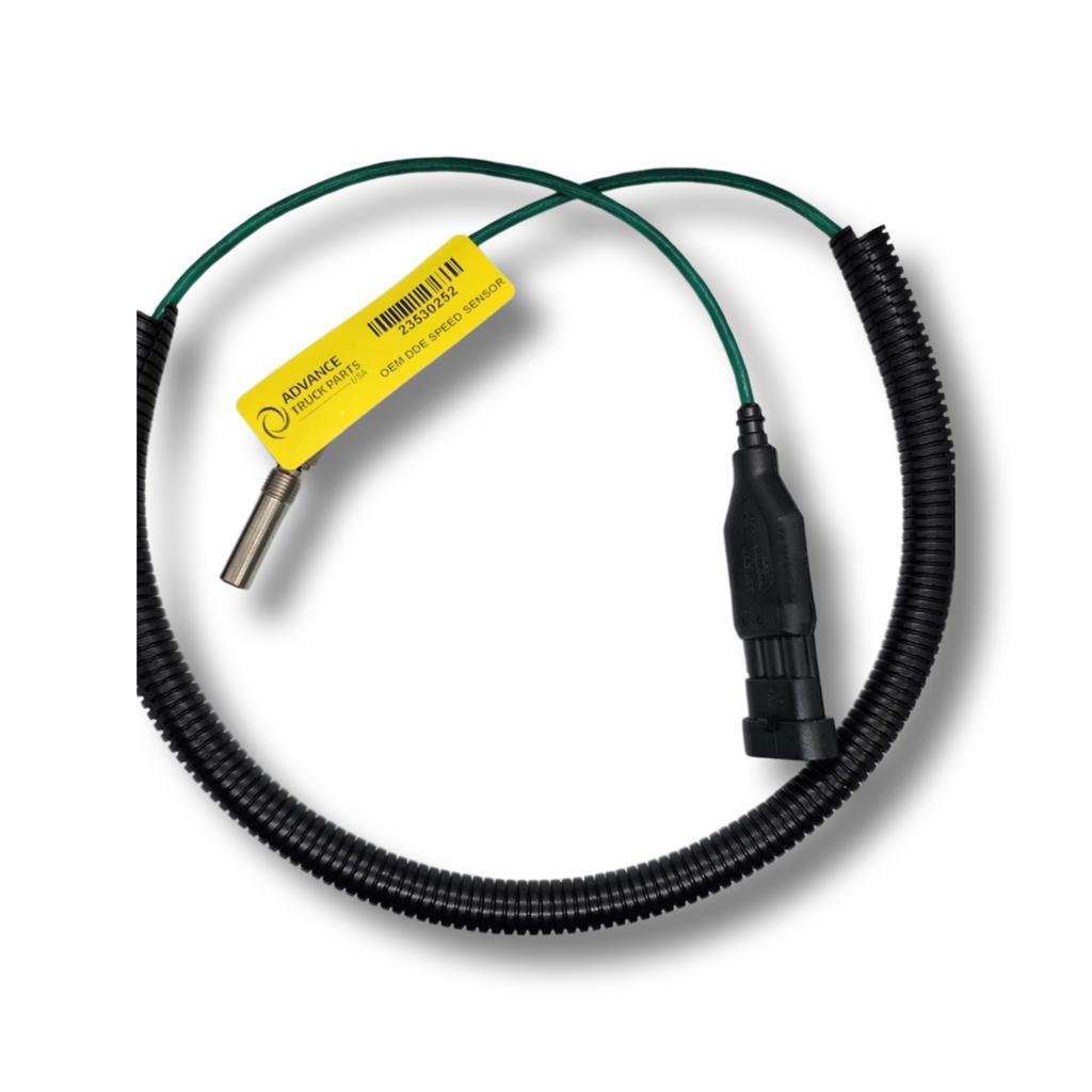 Advance Truck Parts USA 23530252 genuine Detroit Diesel turbocharger speed sensor showing a close-up studio perspective of the threaded metal probe, yellow identification tag, protective corrugated loom, and electrical connector