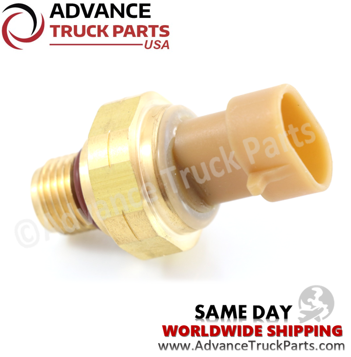 Advance Truck Parts USA branded studio angled perspective showcasing the heavy-duty pressure sensor highlighting the brass hex housing, threaded base with red sealing O-ring, and tan plastic connection port for Cummins engines