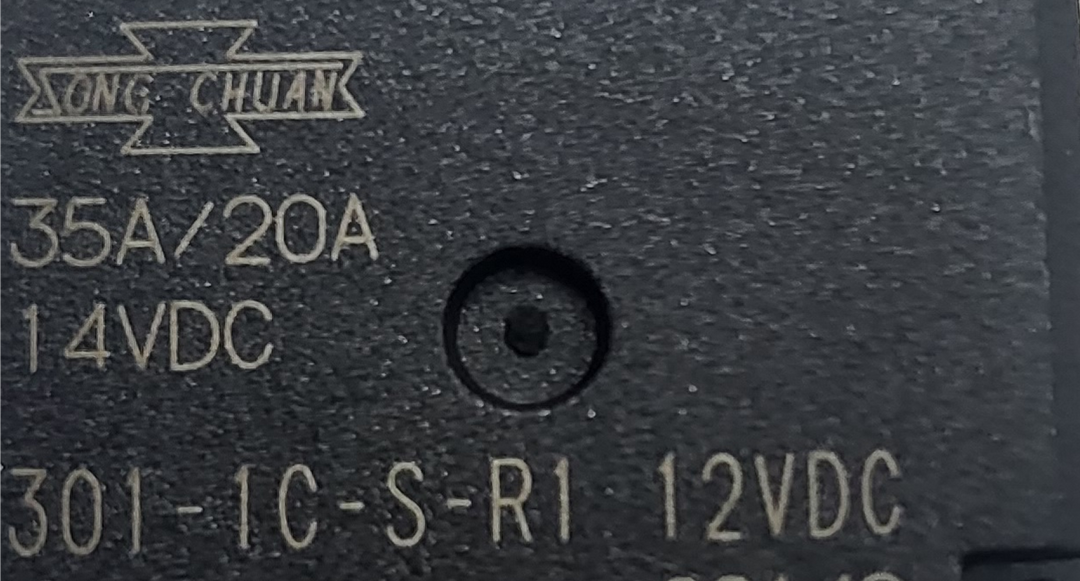 Studio close-up macro perspective highlighting the printed factory specifications, 35A/20A amperage ratings, coil voltage, and manufacturer logo on the top of the black Song Chuan micro automotive relay